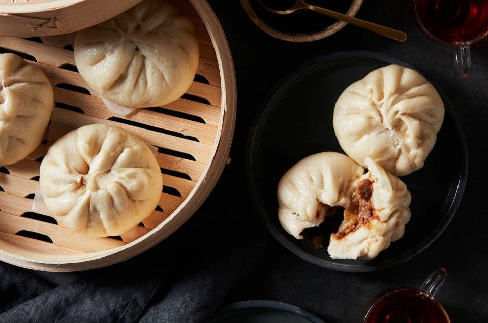 Steamed buns next to steamer full of buns